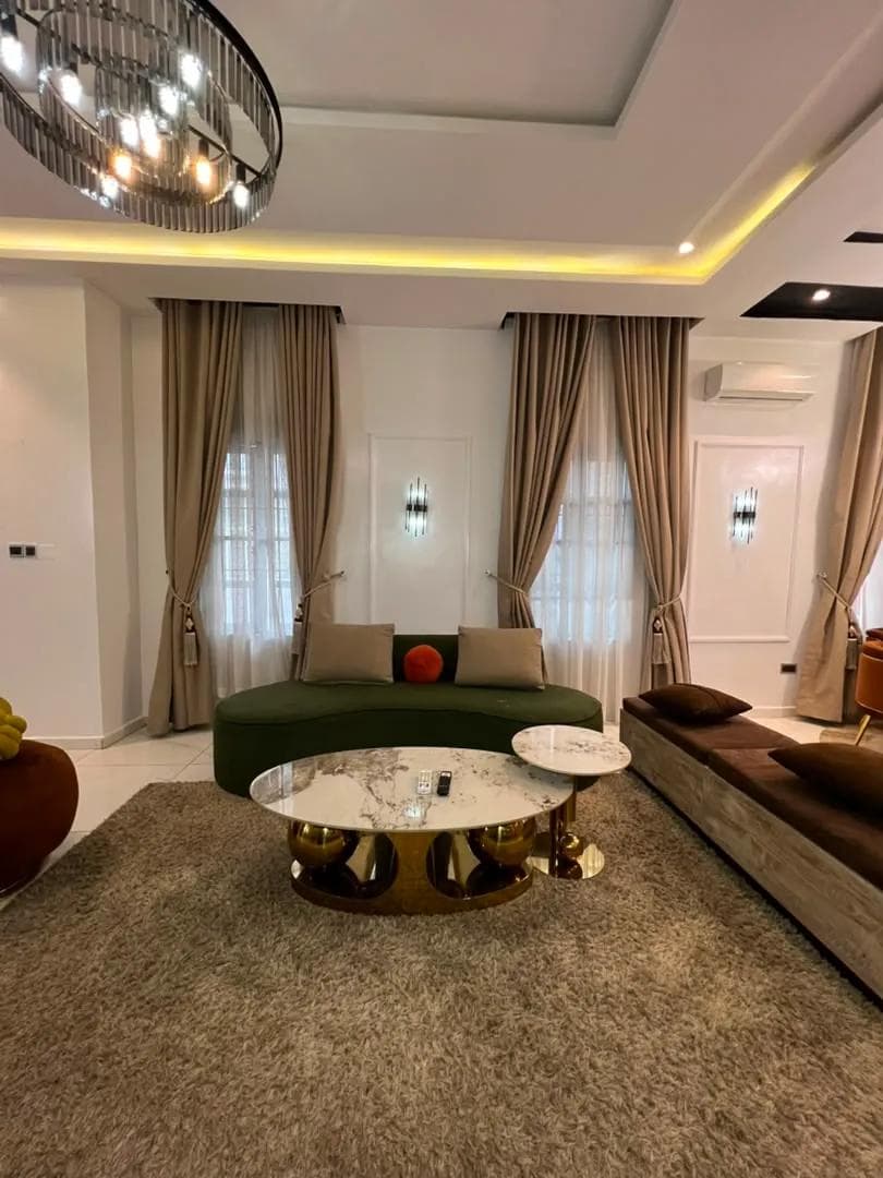 Sitting room with a curved green sofa and gold coffee tables