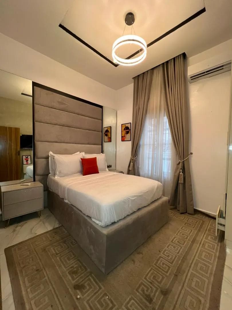 Short-let bedroom with an upholstered headboard and ring pendant