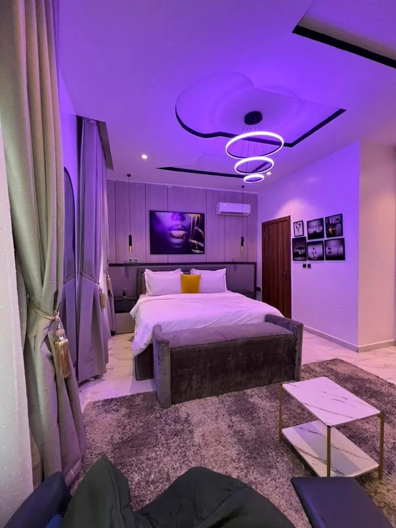 Bedroom lit by a sculptural ceiling light and cove lighting