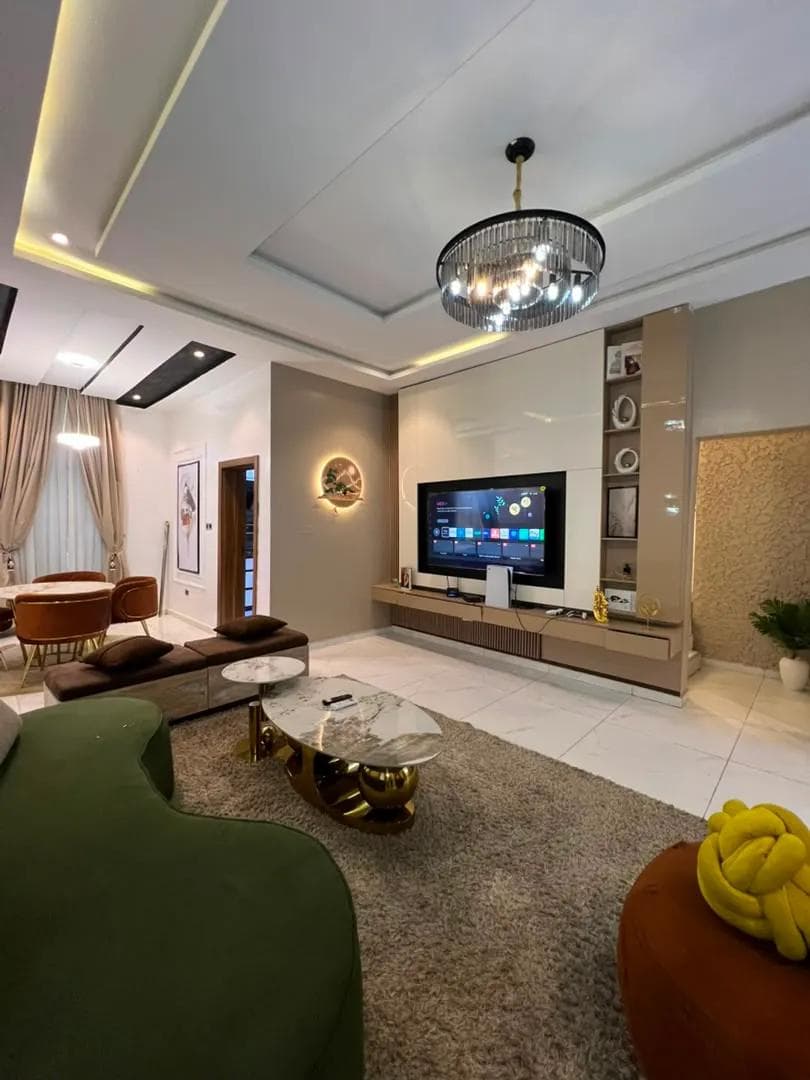 Open-plan short-let living room with a green sectional and marble floors